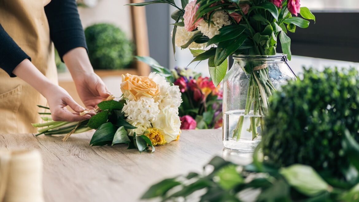 Florist arranging a vibrant flower bouquet on a wooden table